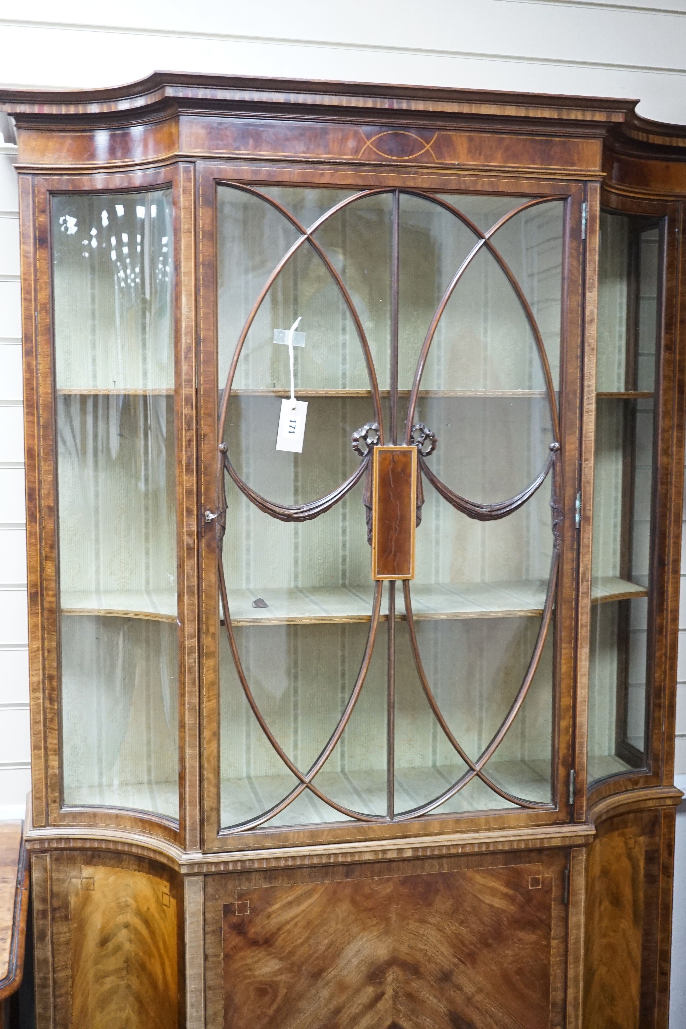 A Sheraton Revival mahogany display cabinet, crossbanded and inlaid, shape fronted, single glazed door on splay bracket feet, width 113cm, depth 36cm, height 198cm